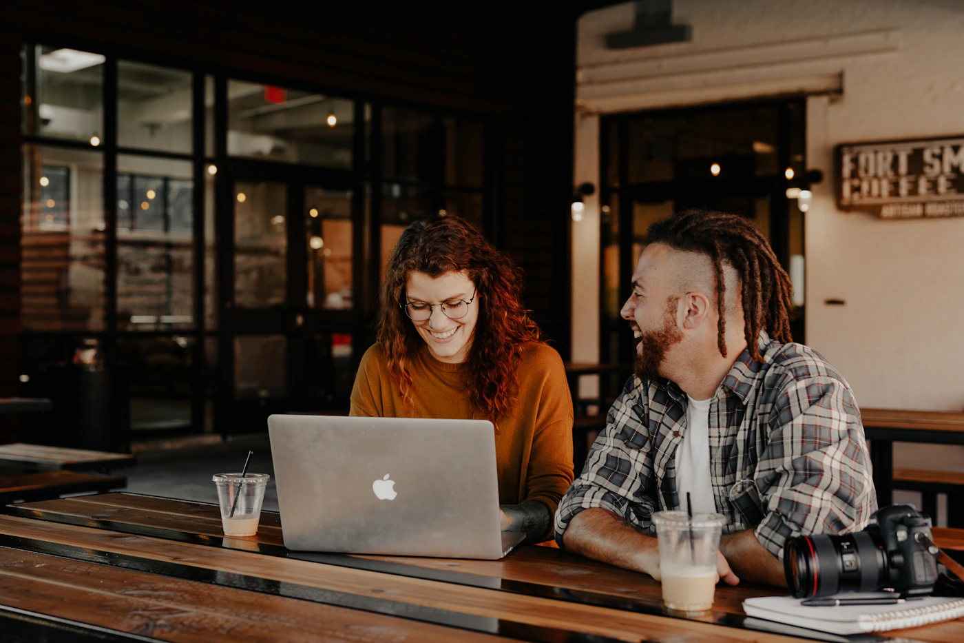Two people smiling while working together at a café table
