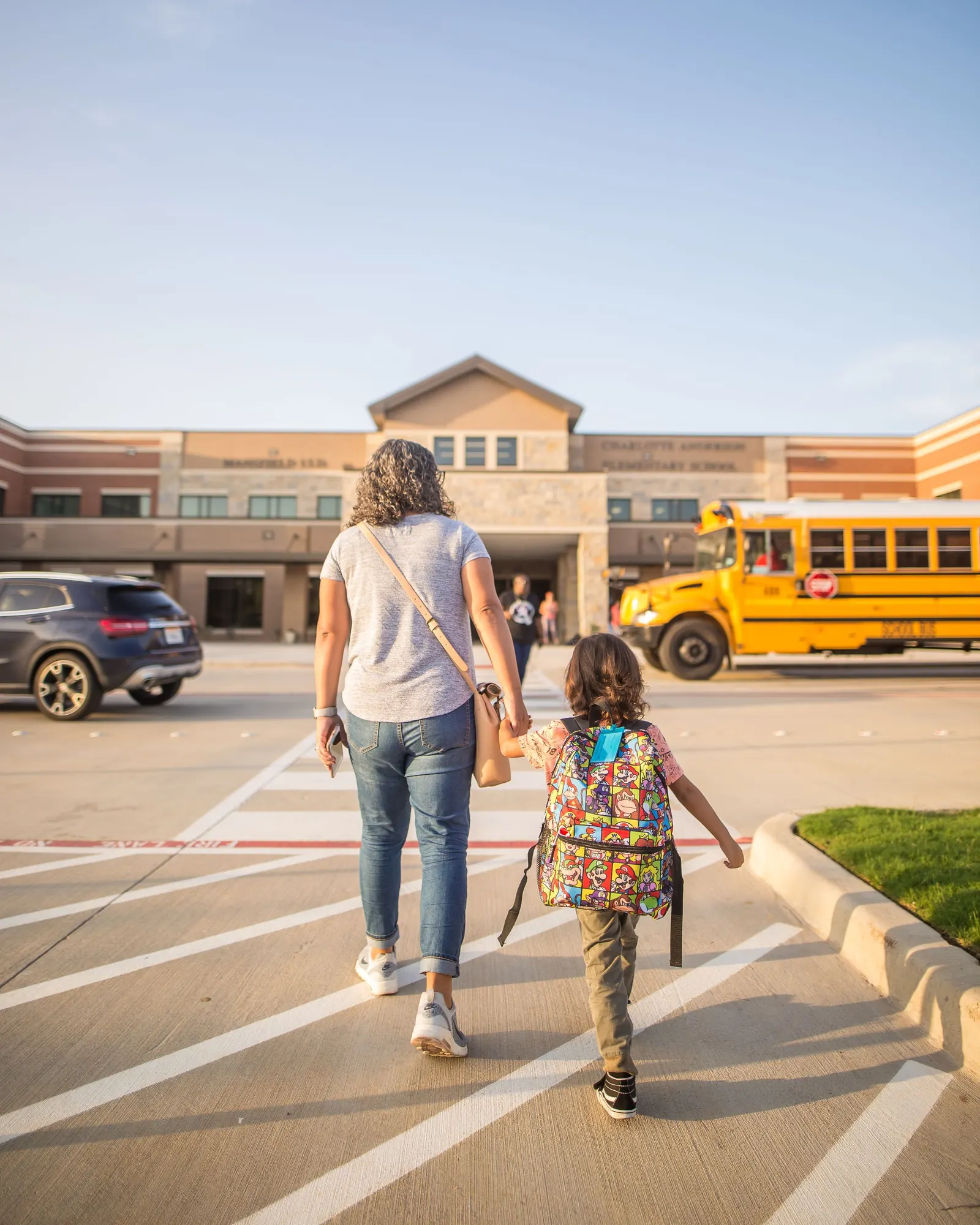 A parent and child on the walk to school, the bus already waiting